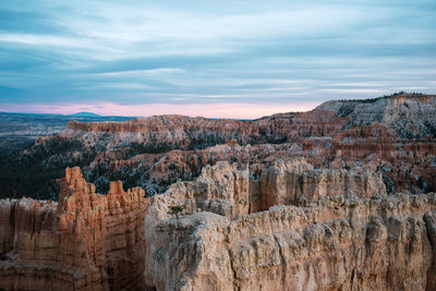 Scenic view of rock formations against cloudy sky