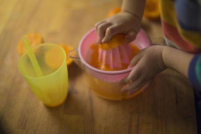 Midsection of child holding drink on table