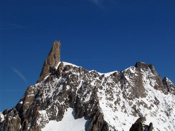 Low angle view of snowcapped mountain against clear blue sky