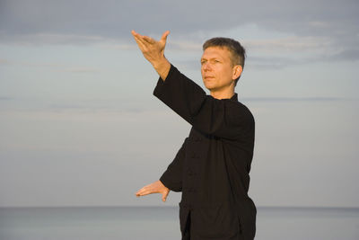 Man standing on beach against sky during sunset