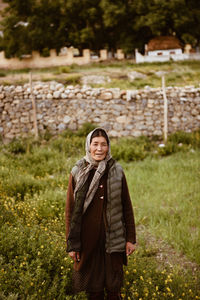 Portrait of smiling young woman standing against trees