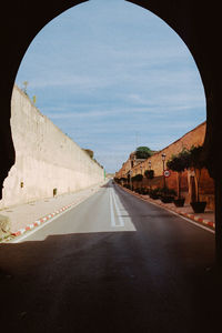 Road leading towards city against sky