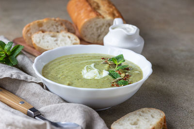 Broccoli cream soup served with mint, cream, seeds and bread. healthy vegetarian food concept. 