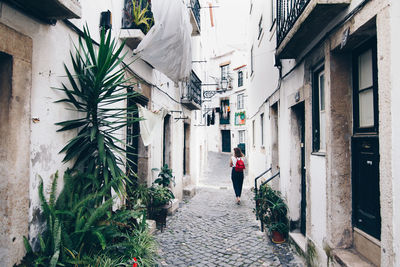 Rear view of woman walking on footpath amidst buildings