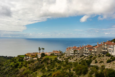 Scenic view of sea by buildings against sky