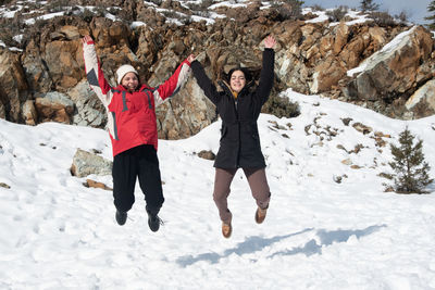 Two young happy teenage girls jumping with pleasure at snow. 