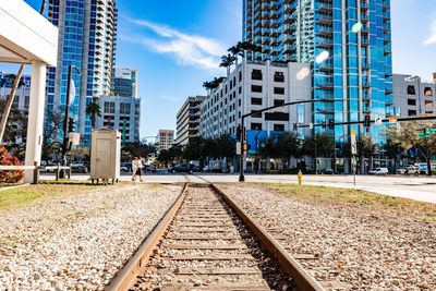 Railroad tracks amidst buildings in city against sky