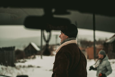 Man on snowy field seen through car windshield