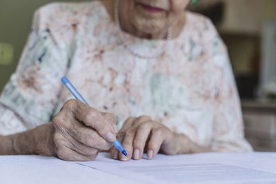 Senior woman signing contract papers on table