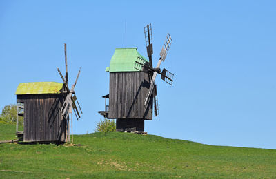 Windmill on grassy field against clear sky