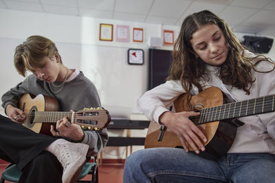 Teenagers attending guitar lesson