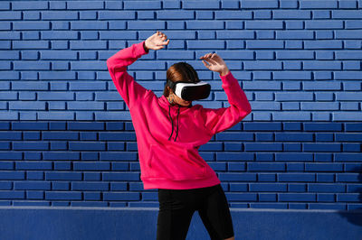 Rear view of woman standing against brick wall