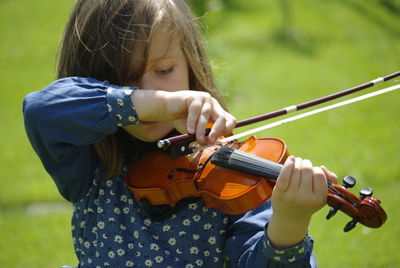 Close-up of girl playing violin while standing field