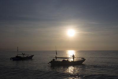 Silhouette boat sailing on sea against sky during sunset