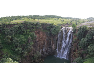 Scenic view of waterfall in forest against sky