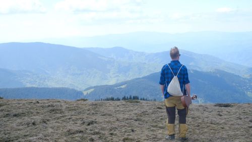 Rear view of man looking at mountains against sky