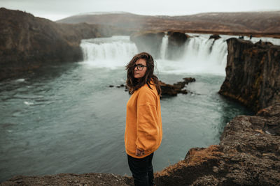 Back view woman between wild lands with waterfall