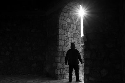 Rear view of silhouette man standing against illuminated building