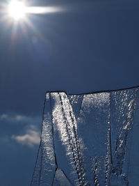 Low angle view of icicles against blue sky on sunny day