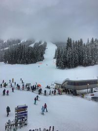 People on snow covered landscape against sky