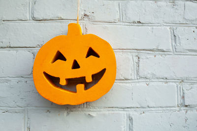 Close-up of jack o lantern figurine hanging on brick wall