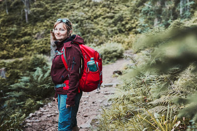 Woman with backpack hiking in mountains, spending summer vacation close to nature