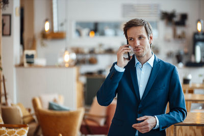 Smiling freelancer talking on smart phone at cafe