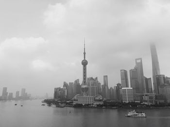 City at waterfront against cloudy sky