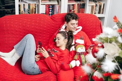 Young couple sitting on red sofa during christmas at home