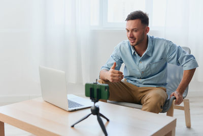 Portrait of young man using mobile phone while sitting on table