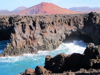 Scenic view of rocks in sea against mountains