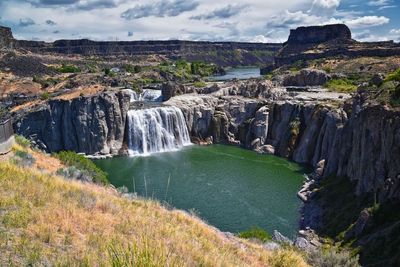 Scenic view of waterfall against sky