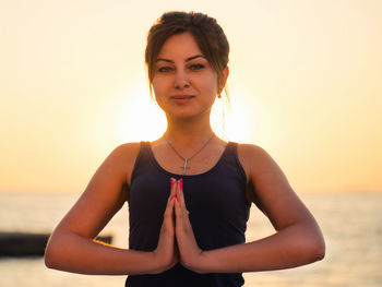 Portrait of woman doing yoga against sky