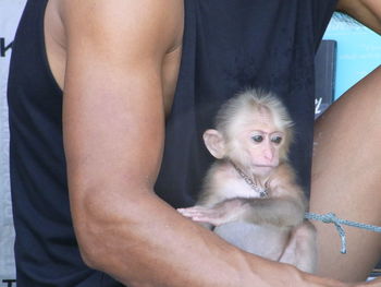 Midsection of man with monkey sitting outdoors