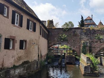 Buildings by river against sky