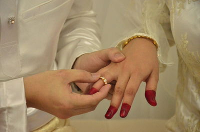 Midsection of man putting ring on bride finger during wedding ceremony