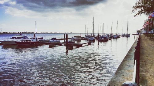 Boats in sea against cloudy sky