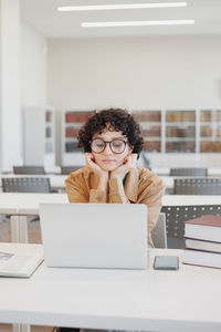 Young woman using laptop at desk in office