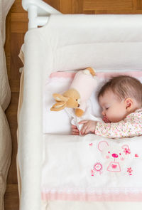 High angle view of baby girl sleeping in crib at home