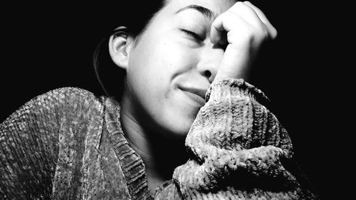 Close-up of young woman eating food against black background