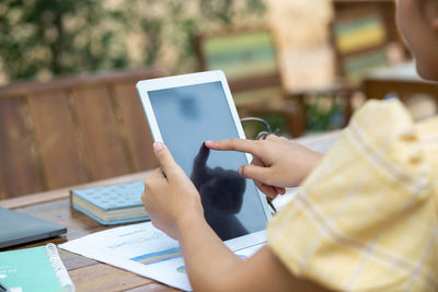 Midsection of woman using mobile phone on table