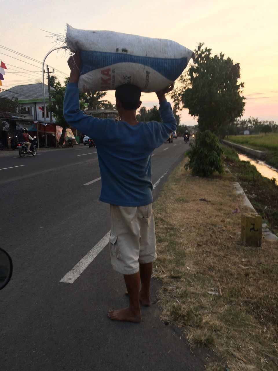 REAR VIEW OF MAN STANDING ON ROAD