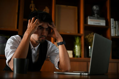 Frustrated man looking at laptop in office