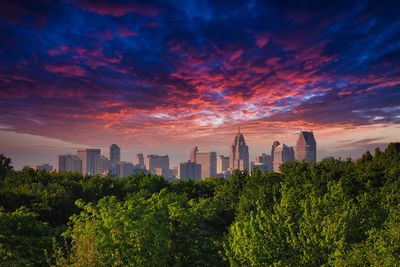 Trees and buildings against sky during sunset