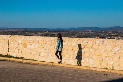 Full length of girl walking on footpath against sky