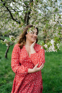 Happy woman standing by red flowering plant