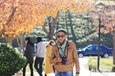 Young man photographing in park during autumn