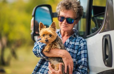 Woman holding dog while standing by vehicle