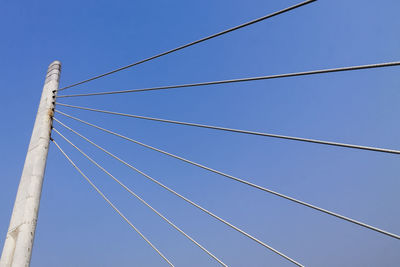 Low angle view of cables on bridge against clear blue sky