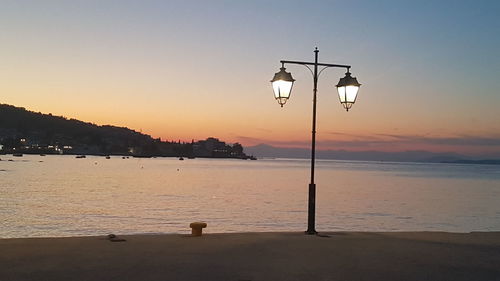 Street light on beach against sky during sunset